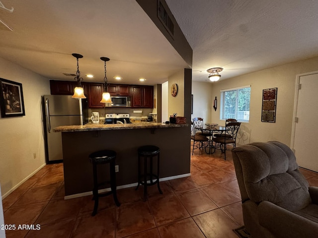 12123 W Bell Rd Unit 337, Surprise, AZ 85378 - kitchen featuring stainless steel appliances, open floor plan, dark tile patterned floors, a kitchen breakfast bar, and a peninsula
