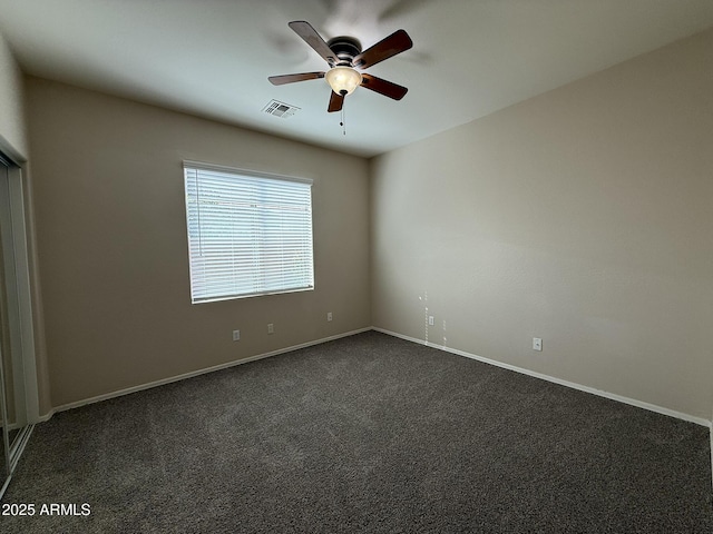 empty room with baseboards, visible vents, dark carpet, and a ceiling fan