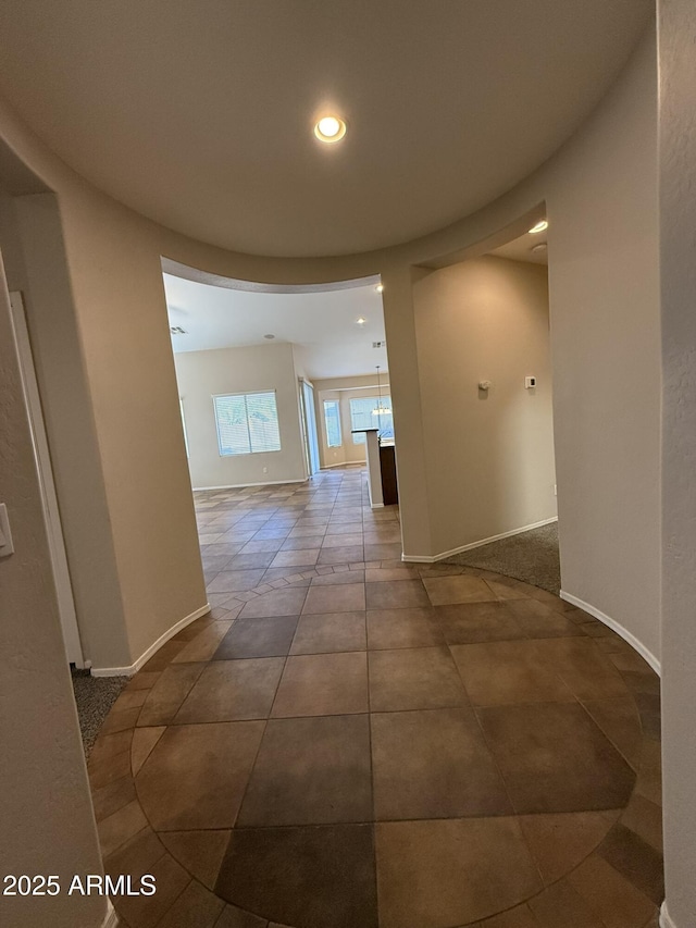 hall with dark tile patterned flooring, baseboards, and recessed lighting