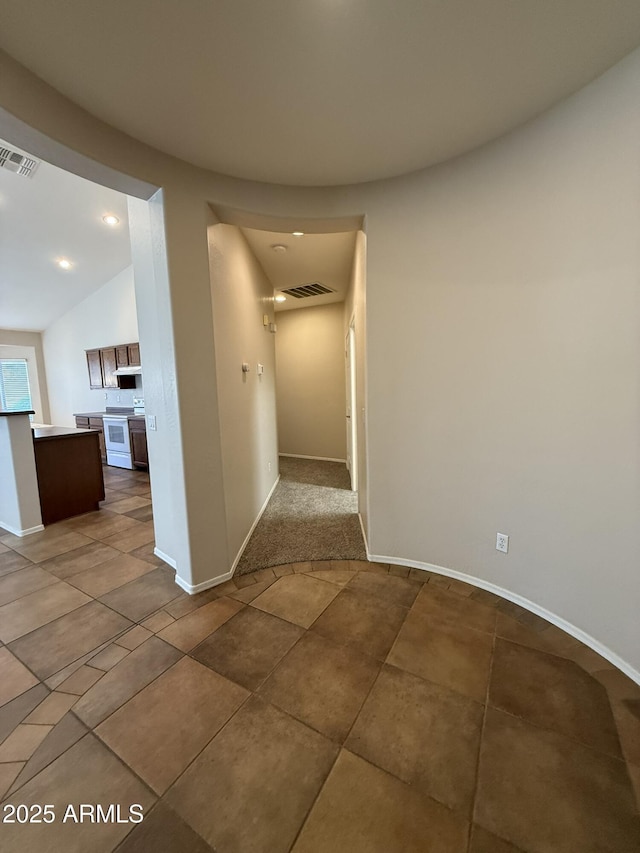 hallway featuring tile patterned flooring, visible vents, and baseboards