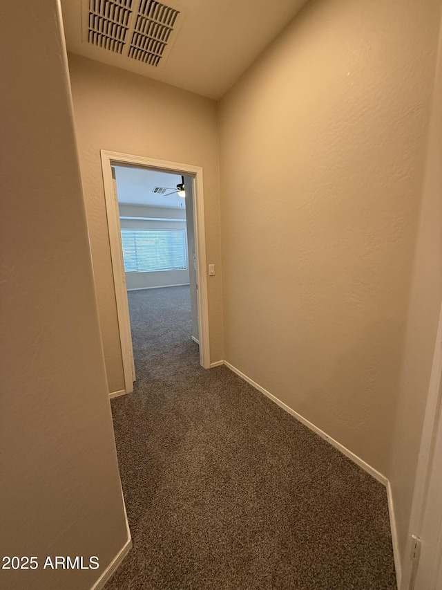 hall featuring baseboards, visible vents, and dark carpet