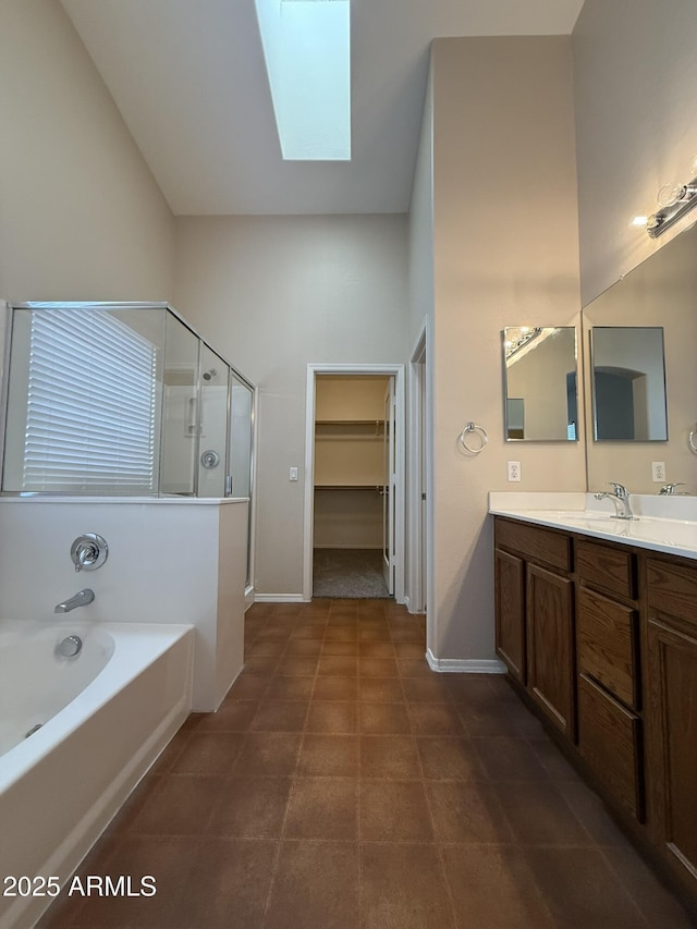 bathroom with a skylight, a spacious closet, vanity, a shower stall, and a bath