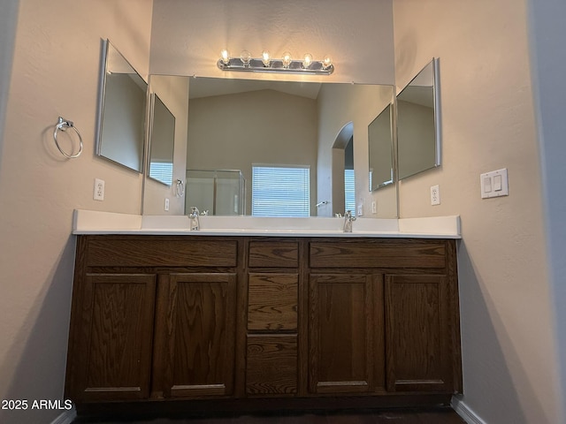 full bathroom with double vanity, vaulted ceiling, and a sink