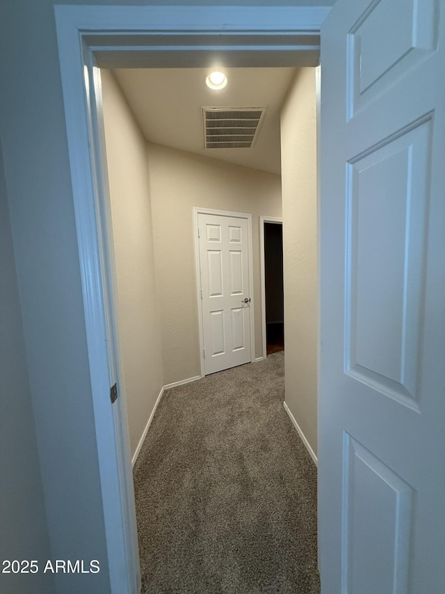 hall featuring baseboards, visible vents, and carpet flooring