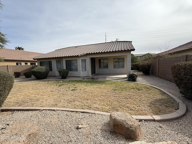 back of house featuring a tile roof, a patio area, a fenced backyard, and stucco siding