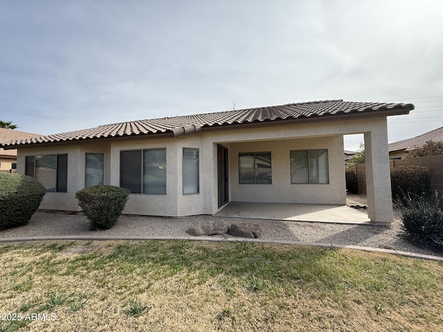 rear view of property with a tile roof, a yard, stucco siding, a patio area, and fence