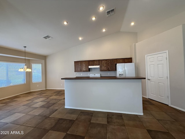 kitchen with dark countertops, white appliances, under cabinet range hood, and visible vents