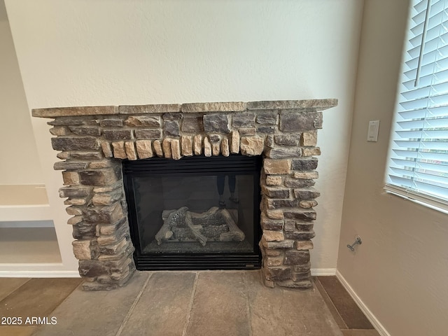 details featuring baseboards and a stone fireplace