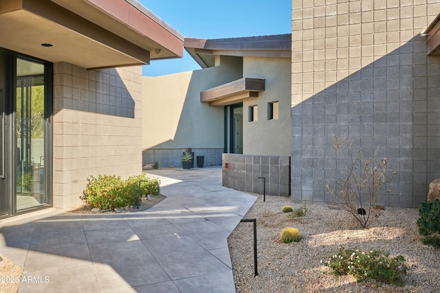 view of exterior entry featuring a patio and stucco siding