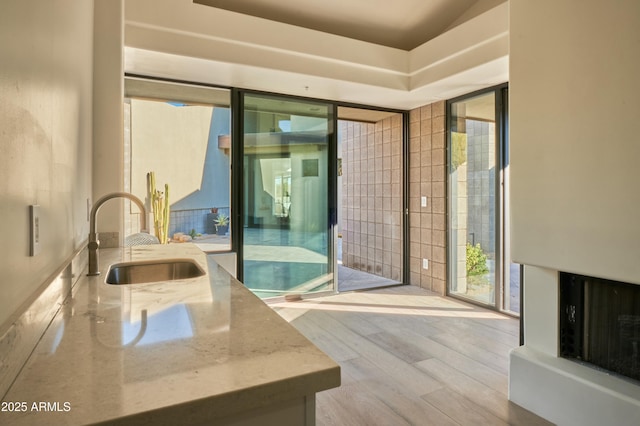 interior space with a wall of windows, sink, and hardwood / wood-style floors