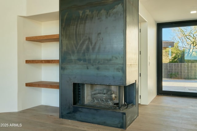 interior details with wood-type flooring and a large fireplace