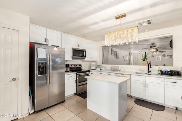 kitchen featuring white cabinetry, sink, hanging light fixtures, stainless steel appliances, and ceiling fan with notable chandelier