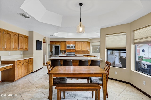 dining area with a tray ceiling, light tile patterned flooring, baseboards, and visible vents