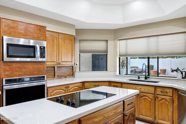 kitchen with brown cabinets, stainless steel appliances, light countertops, and a sink