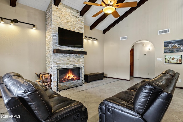 living room featuring tile patterned flooring, visible vents, ceiling fan, beamed ceiling, and arched walkways