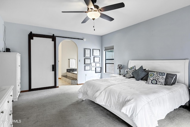 bedroom with a ceiling fan, baseboards, arched walkways, light carpet, and connected bathroom