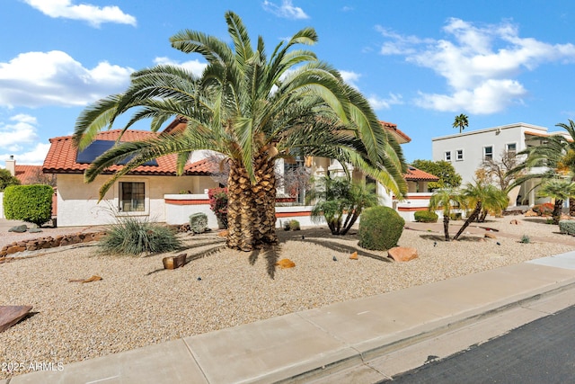 view of front of house with stucco siding, solar panels, and a tiled roof