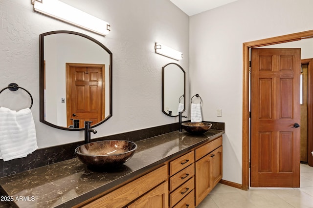 full bathroom with double vanity, tile patterned flooring, and a sink