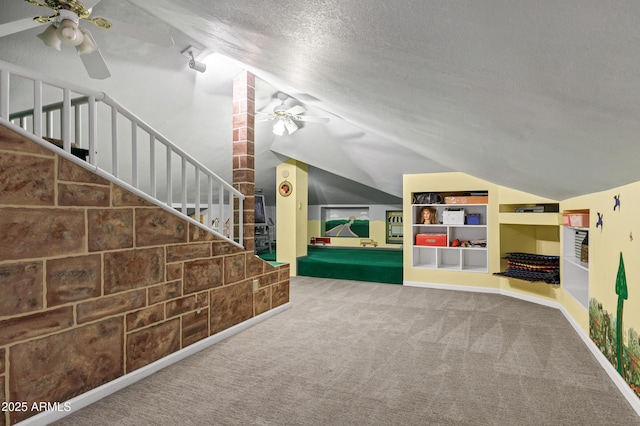 interior space with built in features, a ceiling fan, lofted ceiling, a textured ceiling, and carpet flooring