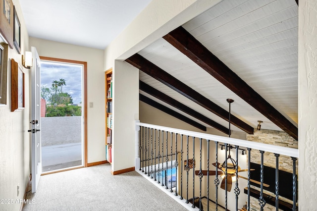 hallway featuring baseboards, carpet, and vaulted ceiling with beams