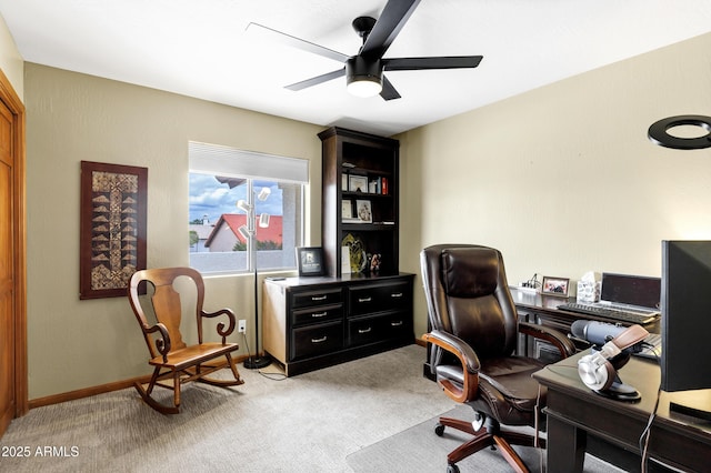 carpeted home office with baseboards and a ceiling fan