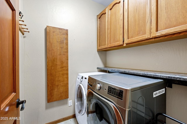 clothes washing area featuring baseboards, cabinet space, and independent washer and dryer