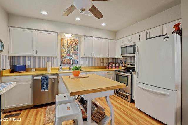 kitchen with ceiling fan, white cabinets, and stainless steel appliances