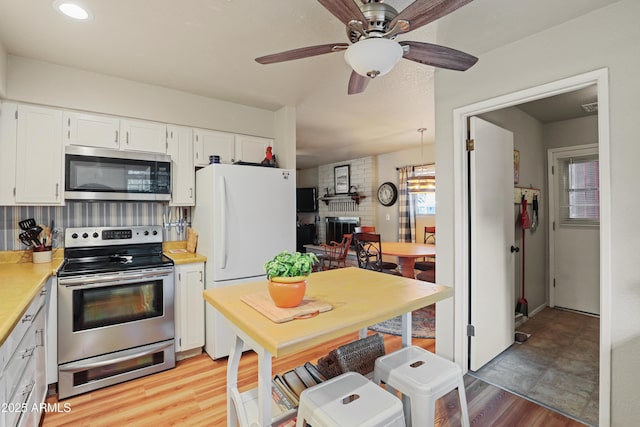 kitchen featuring appliances with stainless steel finishes, light hardwood / wood-style flooring, white cabinetry, and ceiling fan