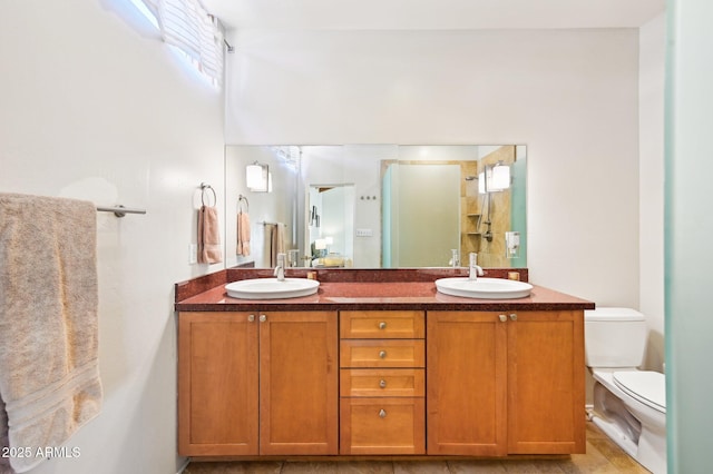 full bathroom featuring double vanity, toilet, a sink, and a shower with shower door