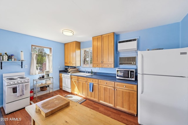 kitchen with white appliances, dark countertops, wood finished floors, a sink, and a wall mounted AC