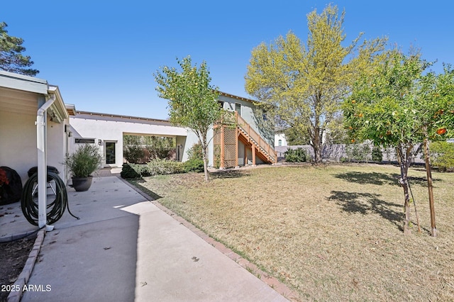 view of yard with a patio area, stairs, and fence