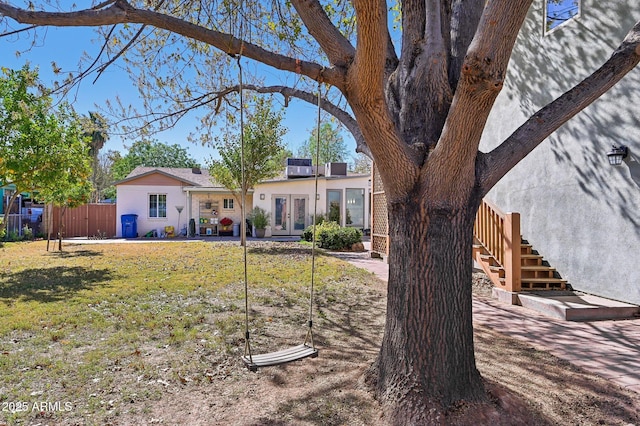 exterior space with fence, a front lawn, and french doors