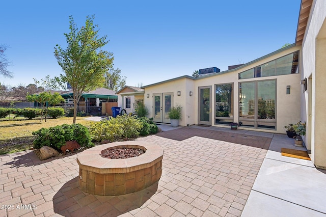 view of patio / terrace featuring an outdoor fire pit, fence, and french doors