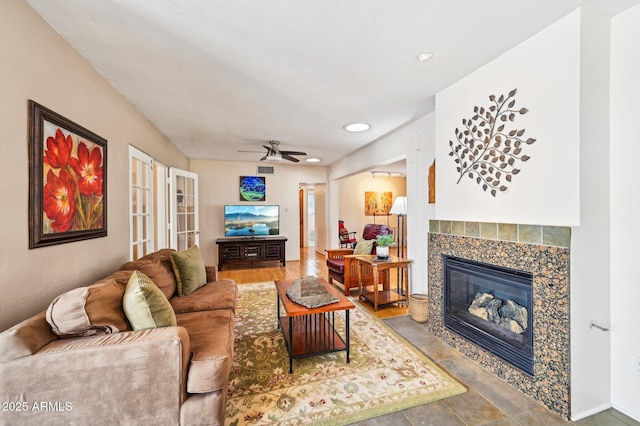 living room featuring visible vents, a tiled fireplace, and a ceiling fan