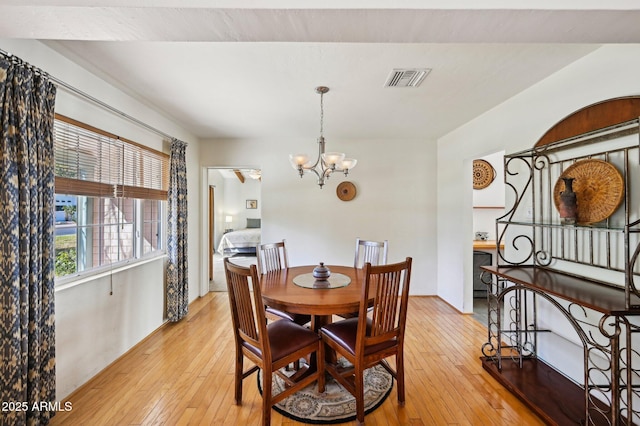 dining room with a chandelier, light wood-type flooring, and visible vents