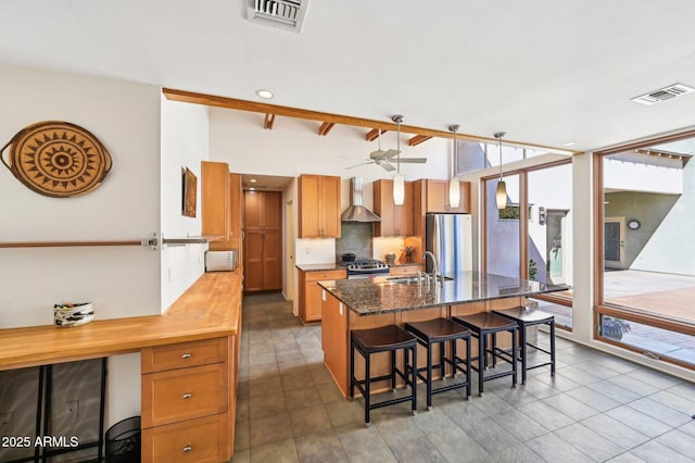 kitchen with wall chimney exhaust hood, visible vents, decorative backsplash, and stainless steel appliances