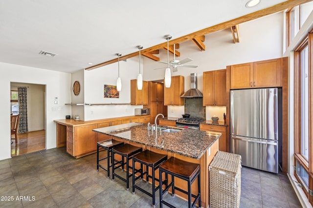 kitchen featuring brown cabinets, wall chimney range hood, visible vents, and stainless steel appliances