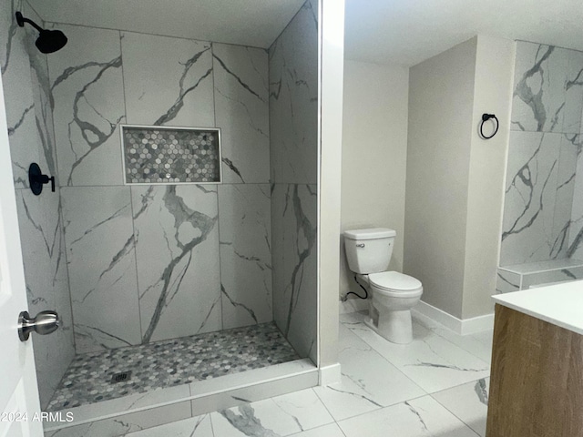 bathroom featuring a tile shower, vanity, and toilet