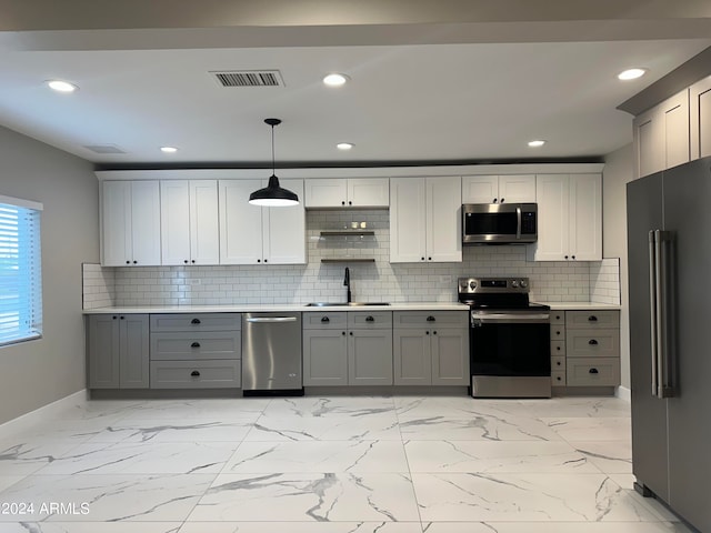 kitchen with hanging light fixtures, decorative backsplash, gray cabinetry, stainless steel appliances, and sink