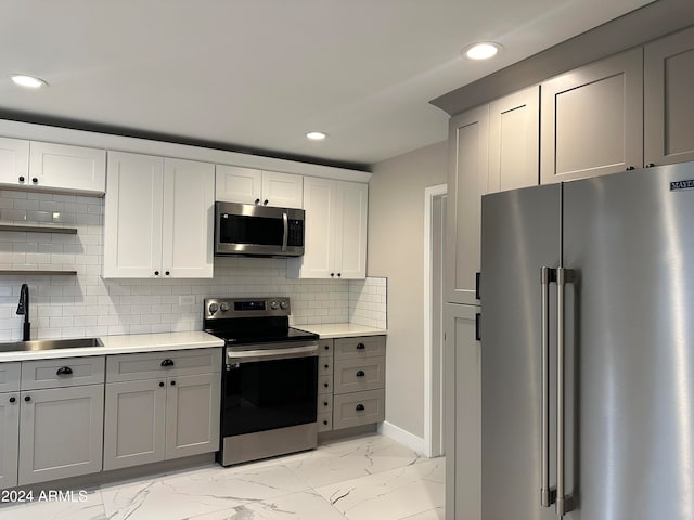 kitchen featuring gray cabinetry, appliances with stainless steel finishes, sink, and decorative backsplash