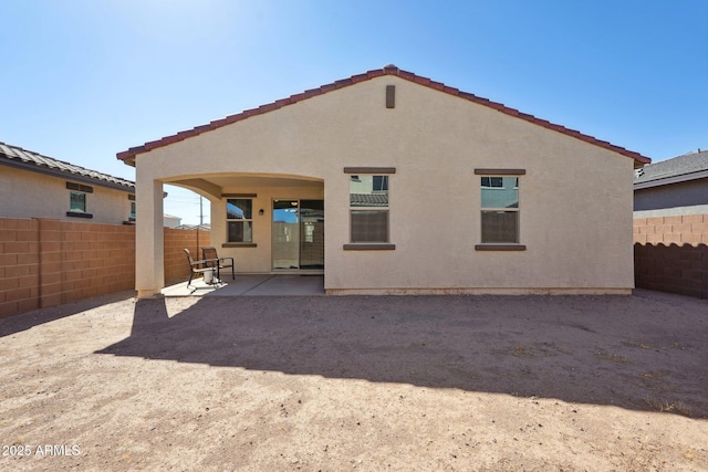 rear view of property featuring a patio, fence, and stucco siding