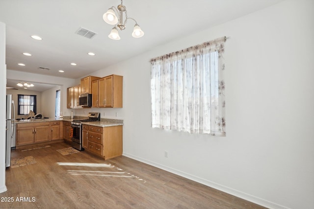 kitchen featuring appliances with stainless steel finishes, a chandelier, visible vents, and wood finished floors