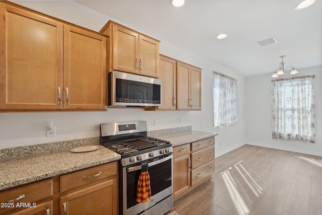 kitchen with light stone counters, recessed lighting, visible vents, appliances with stainless steel finishes, and light wood-style floors