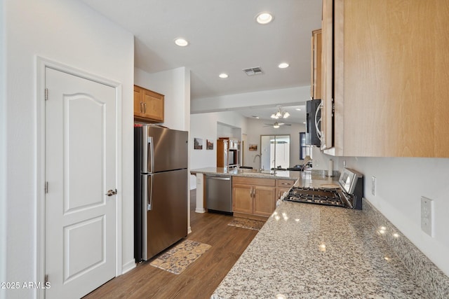 kitchen featuring recessed lighting, a peninsula, dark wood-type flooring, a sink, and appliances with stainless steel finishes