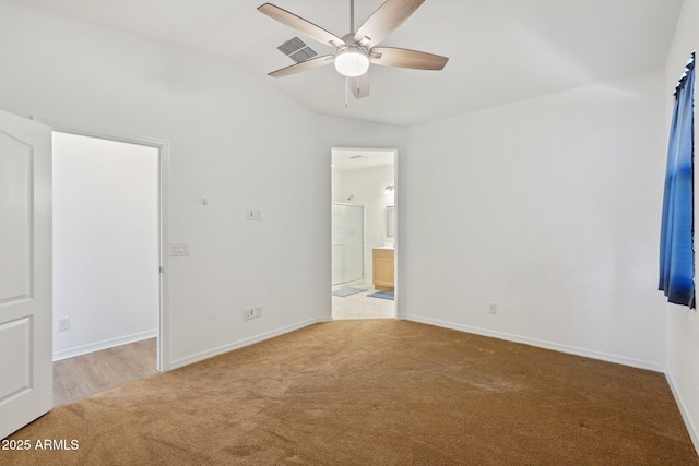 unfurnished bedroom featuring carpet floors, baseboards, ensuite bathroom, and lofted ceiling