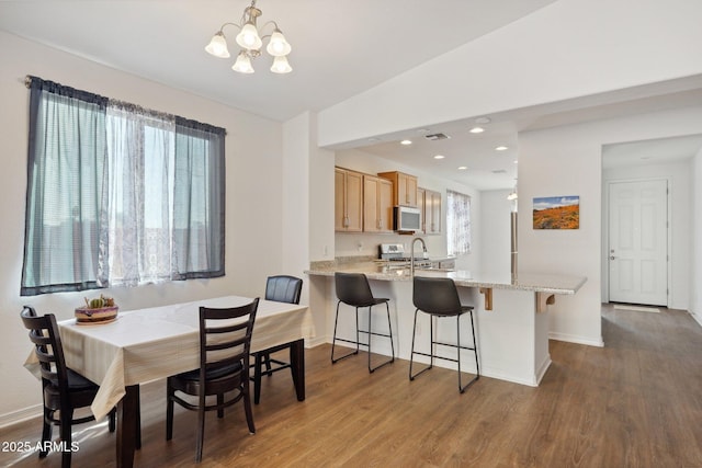 dining space featuring a chandelier, recessed lighting, baseboards, and wood finished floors