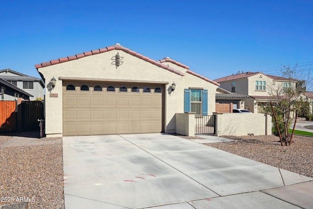 mediterranean / spanish home with driveway, an attached garage, fence, and stucco siding