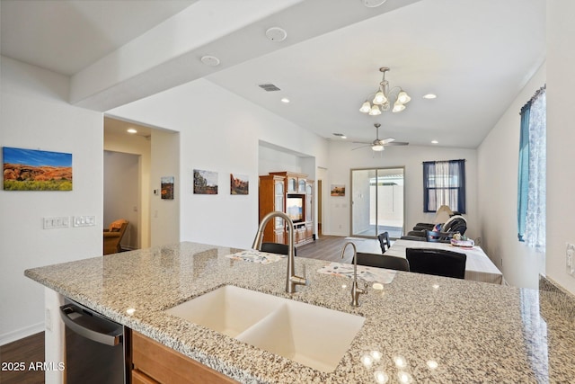 kitchen featuring visible vents, dishwasher, light stone counters, open floor plan, and a sink