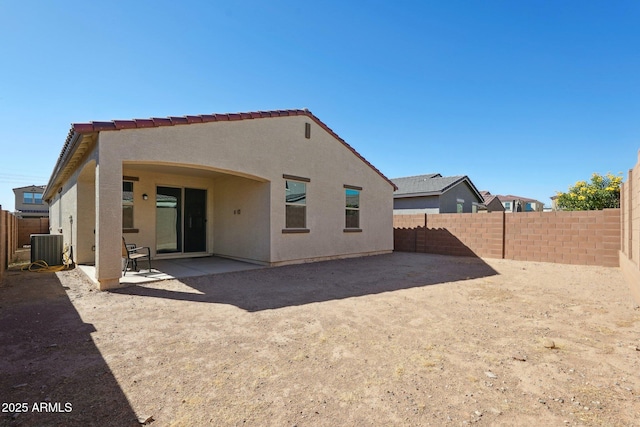 rear view of house featuring stucco siding, a fenced backyard, cooling unit, and a patio