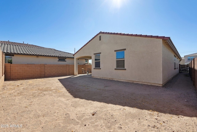 rear view of house featuring a fenced backyard and stucco siding